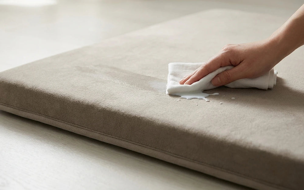 A hand wiping a small spill off the surface with a cloth